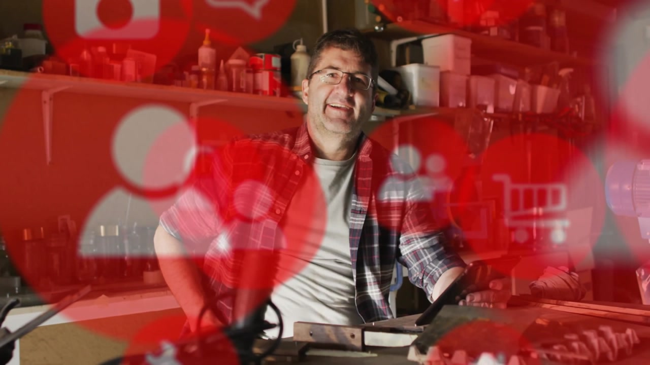 Smiling man in workshop with social media icons animation over background