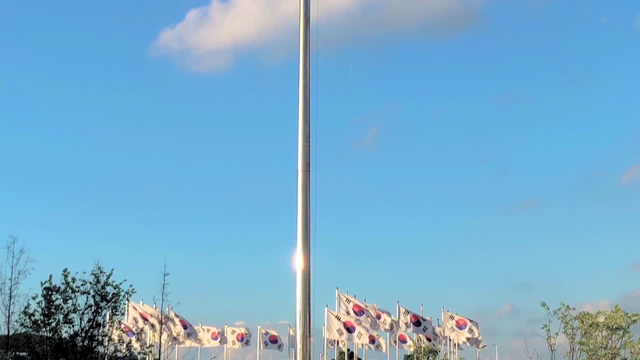 Upwards shot from many korean flags surounding a larger one to the top of the huge south korean flag