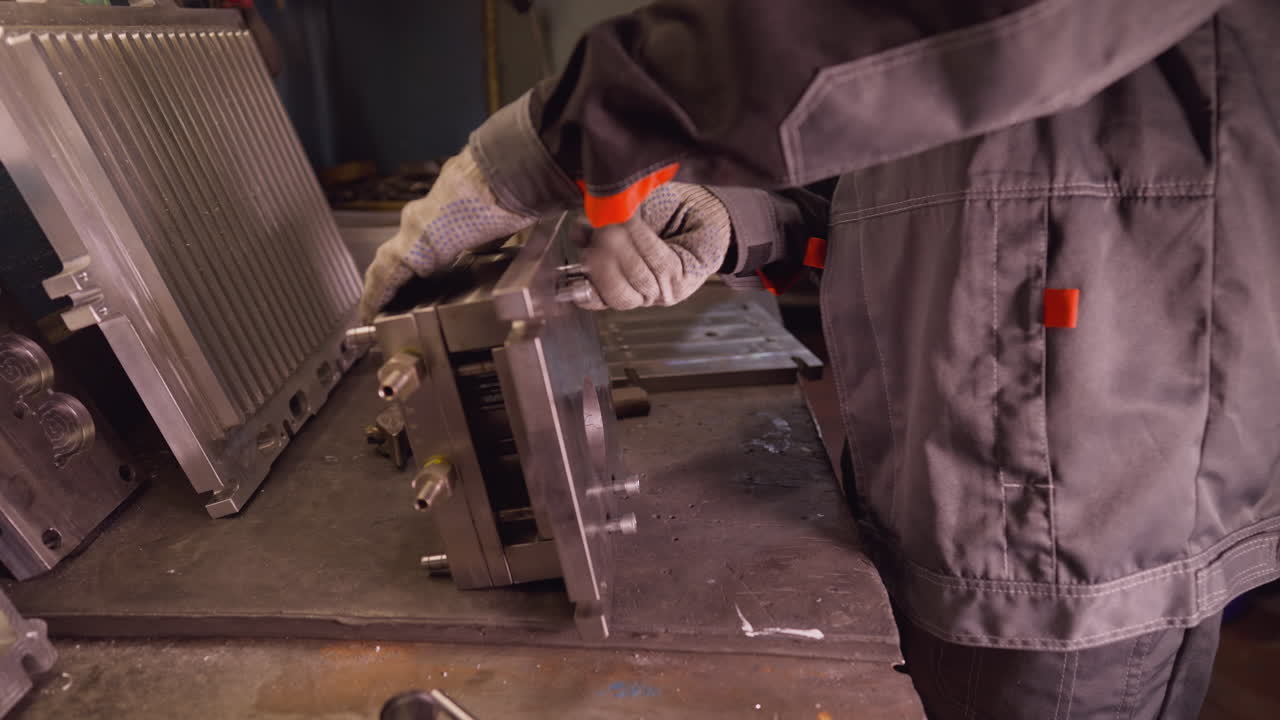 Craftsman in workshop tightening bolts on metal machine parts with a wrench