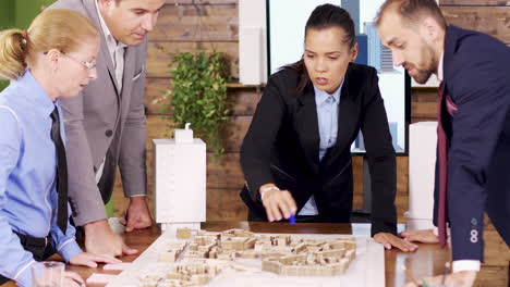 Female-architect-in-the-conference-room-pointing-at-mini-town