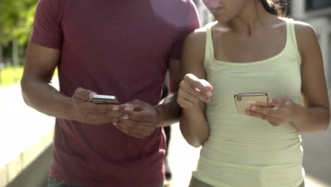 Captura-Recortada-De-Una-Pareja-Sosteniendo-Dispositivos-Mientras-Caminaba-Por-La-Calle.