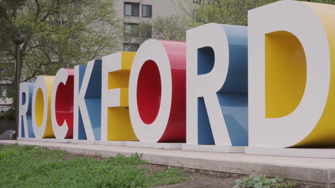 Plano suave e cinematográfico de elevação com gimbal da placa da cidade de Rockford, Illinois, capturado ao ar livre com movimento de câmera vertical estabilizado.