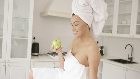 Woman-wrapped-in-towel-eating-apple