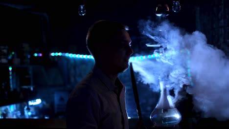 man smoking hookah in a night club