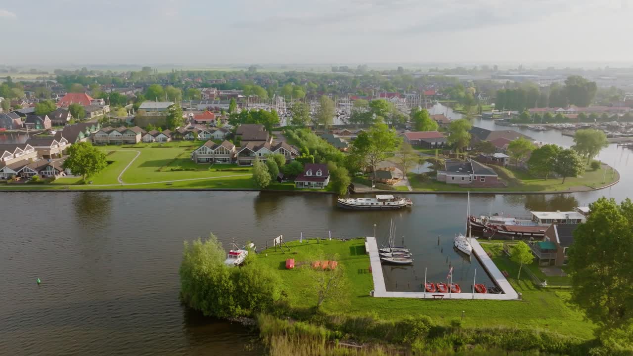 Aerial semi orbit showcasing a Luxemotor boat on the canal of Heeg, Netherlands, with Dutch houses and green surroundings