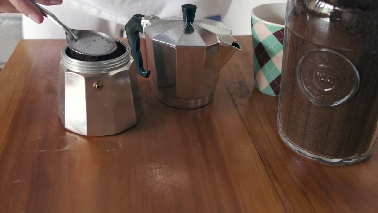 preparación de café de la mañana con olla de moka, taza y terreno