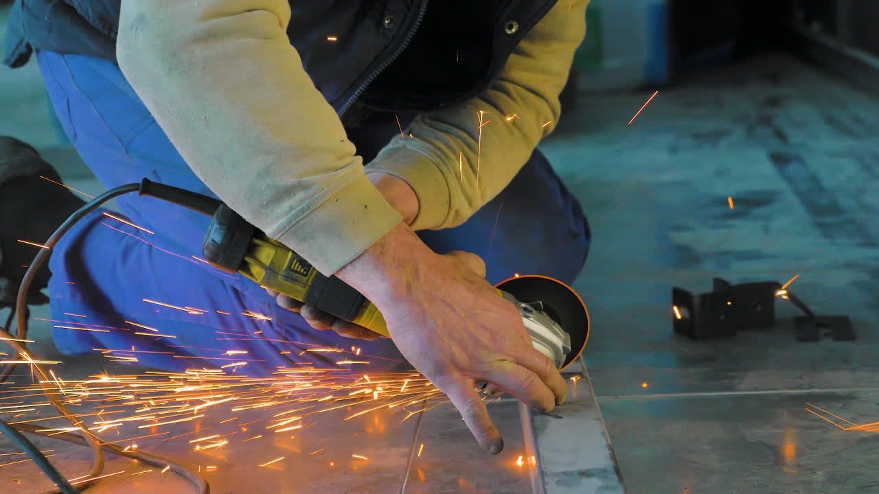 un hombre corta hierro con una sierra circular en el suelo