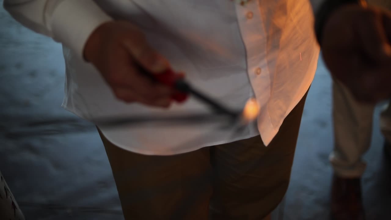 축하 시간 동안 사람들의 폭죽 불꽃놀이를 밝히기 위해 라이터를 사용하는 사람의 슬로우 모션 샷