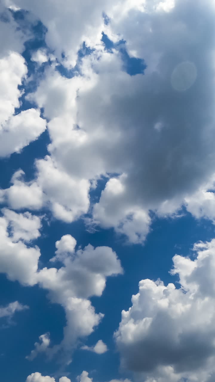 Multiple cotton clouds quickly transforming in the atmosphere. Soft cloudscape formation on sunny daytime. Timelapse. Vertical video