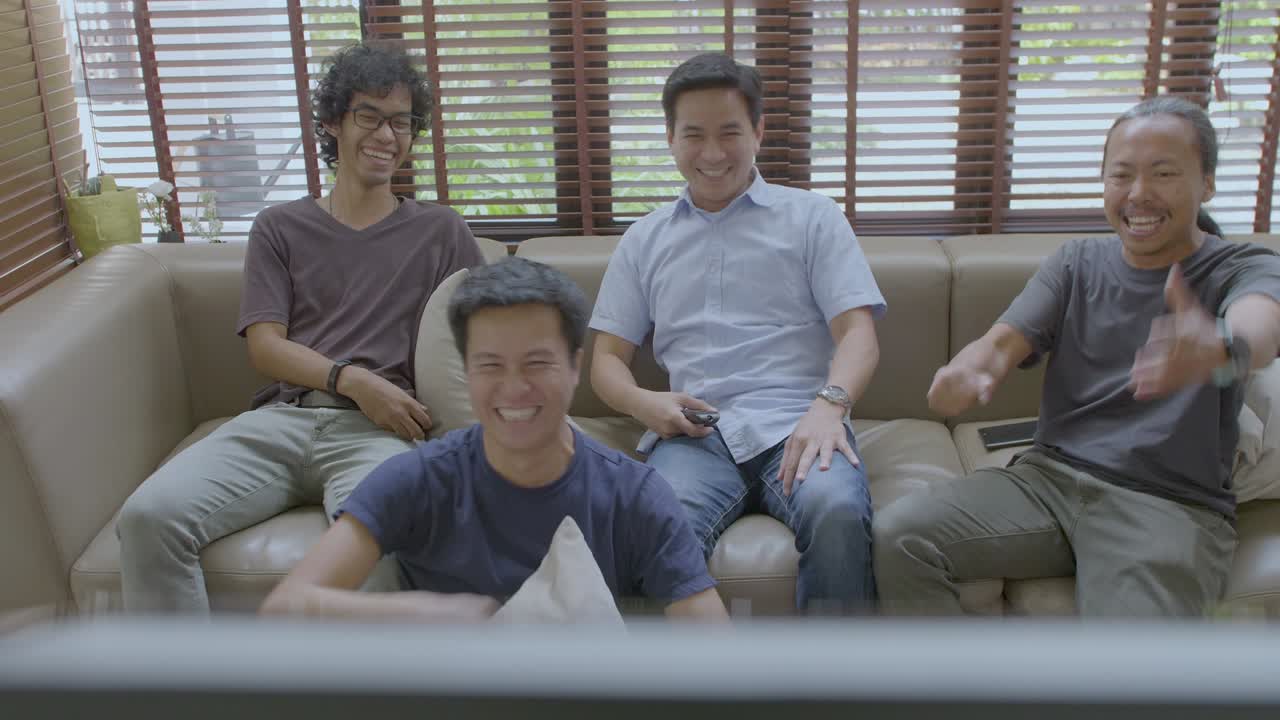 아시안 메이트 그룹이 집에서 tv에서 스포츠 대회를 보고 있습니다.