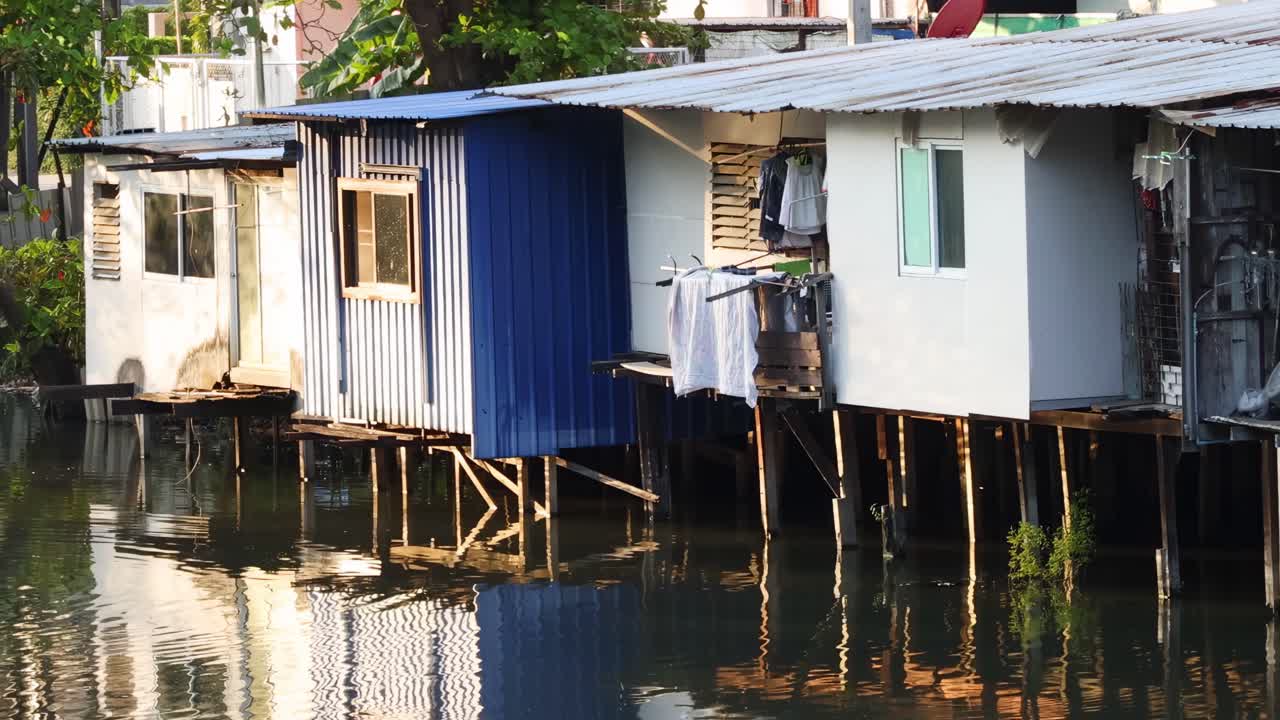 Close-up view of vibrant stilt houses with reflections on calm water, showcasing simple architectural design.