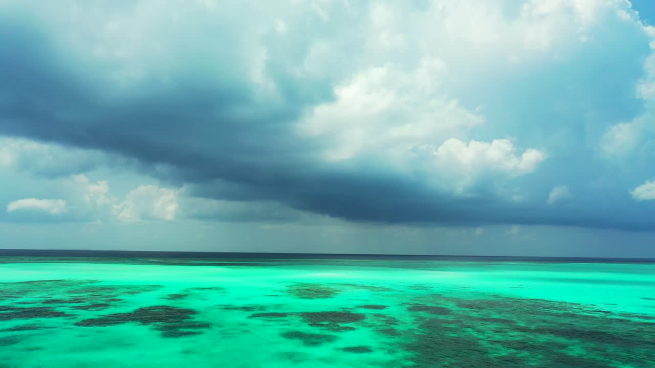 무지개 빛깔의 열대 바다 물과 위의 무거운 폭풍우 구름의 아름다운 풍경