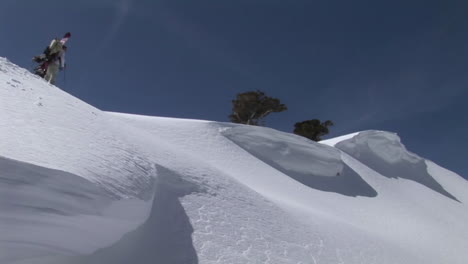 longshot of hikers ascending a snowy mountain with snowboards on their backs