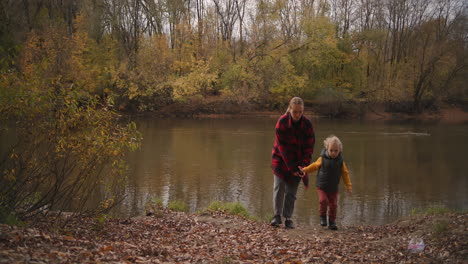casual style clothes for mother and child for walking at nature and active rest woman and boy are walking on coast of lake in woodland family outfit
