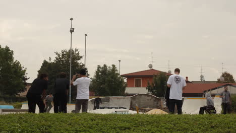 skaters hang out in a suburban park under cloudy skies, blending urban youth culture with a quiet residential backdrop