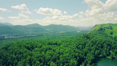 aerial flying over mountains and forest under cloudy sky also in sight is mountain river