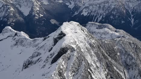 snow capped mountain top and valley, high aerial orbit, sunny day