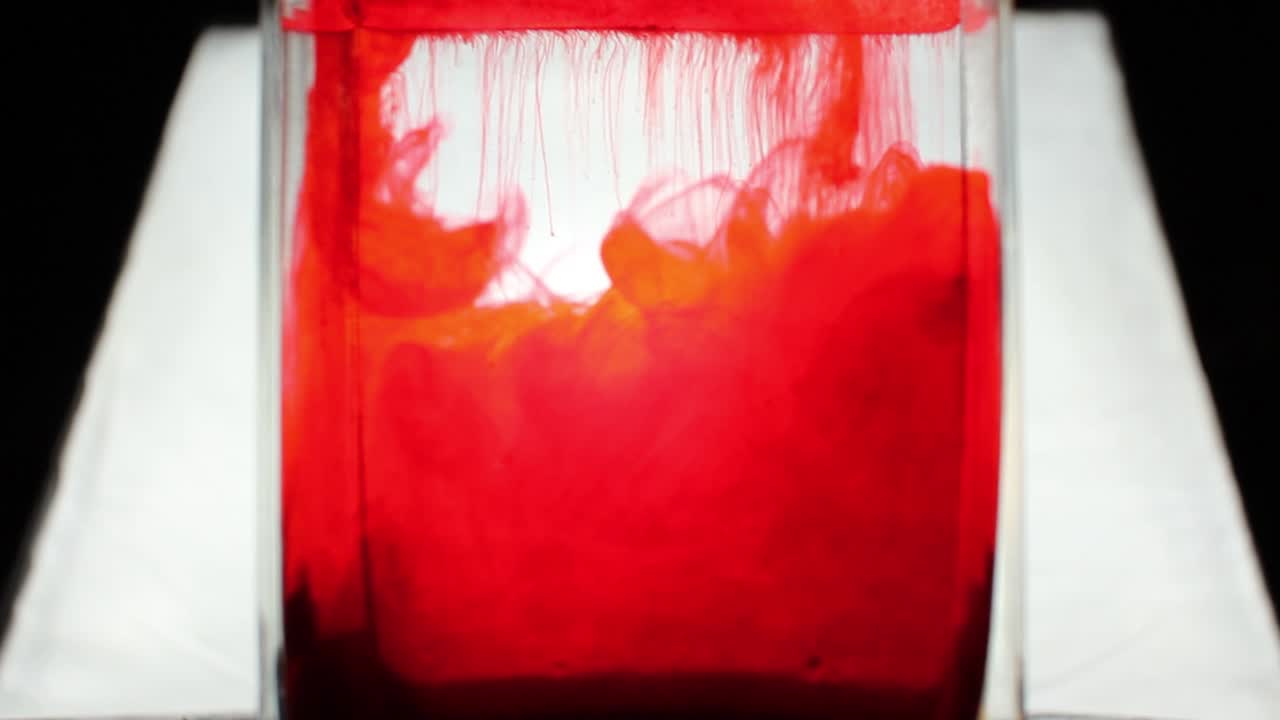 A red colour is pouring into the clean water.