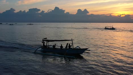 aerial of excited tourists cruising on a boat tour in tropical water of lovina bali indonesia at sunrise