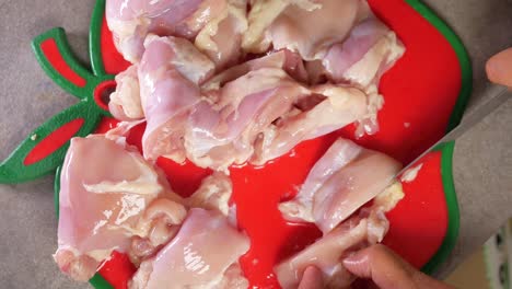 cutting raw chicken on a chopping board