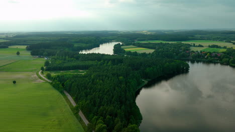 Ein-Ruhiger-See,-Umgeben-Von-üppigen-Grünen-Wäldern-Und-Ackerland-Unter-Einem-Wolkigen-Himmel