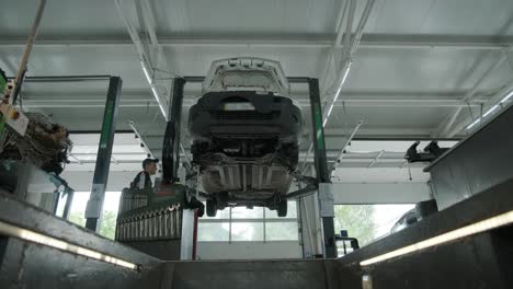 auto mechanic working underneath car lifting machine at the garage. auto repair shop, car service, repair.