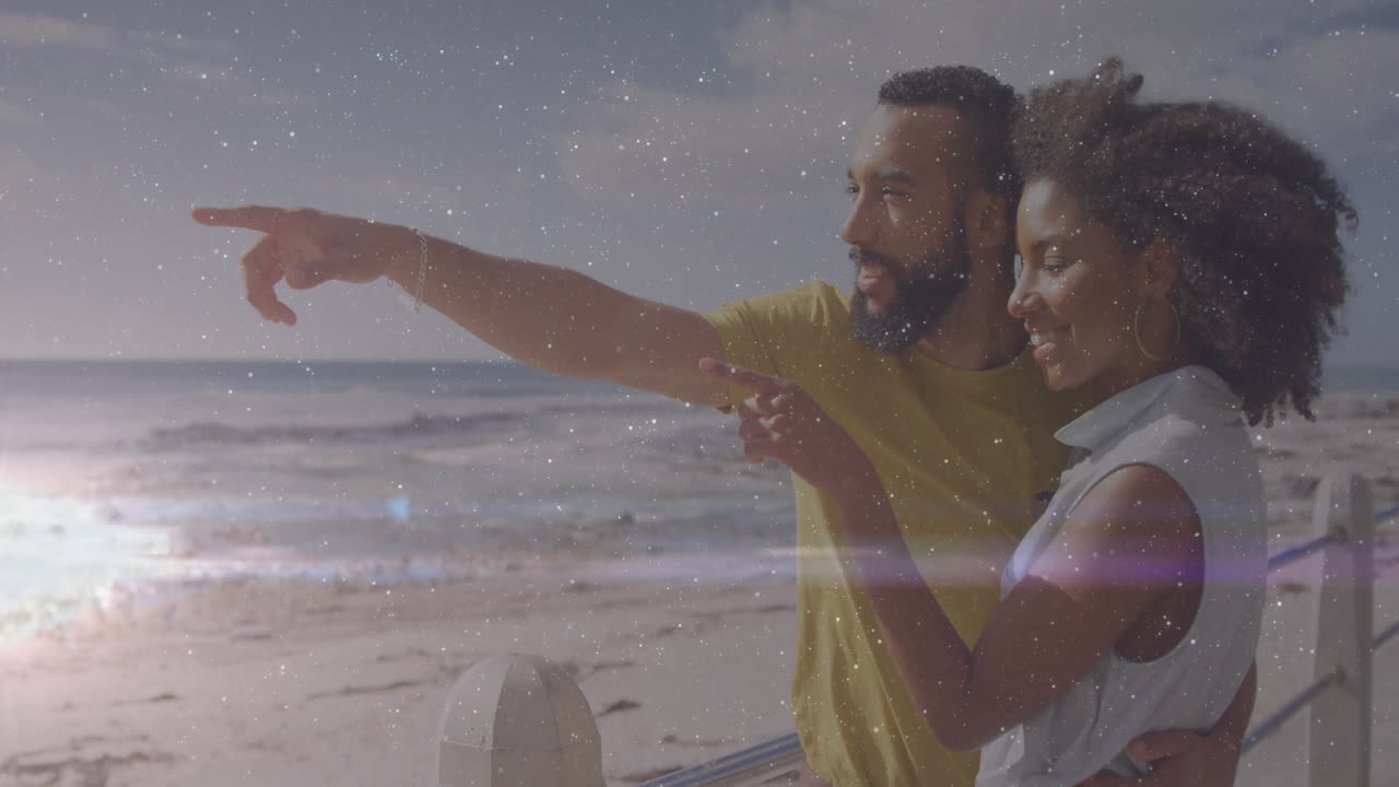 On beach, couple smiling with animation overlay, ocean in background