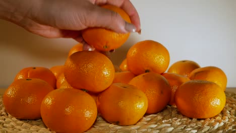 the beautiful female hand is grabbing an orange from the pile of oranges