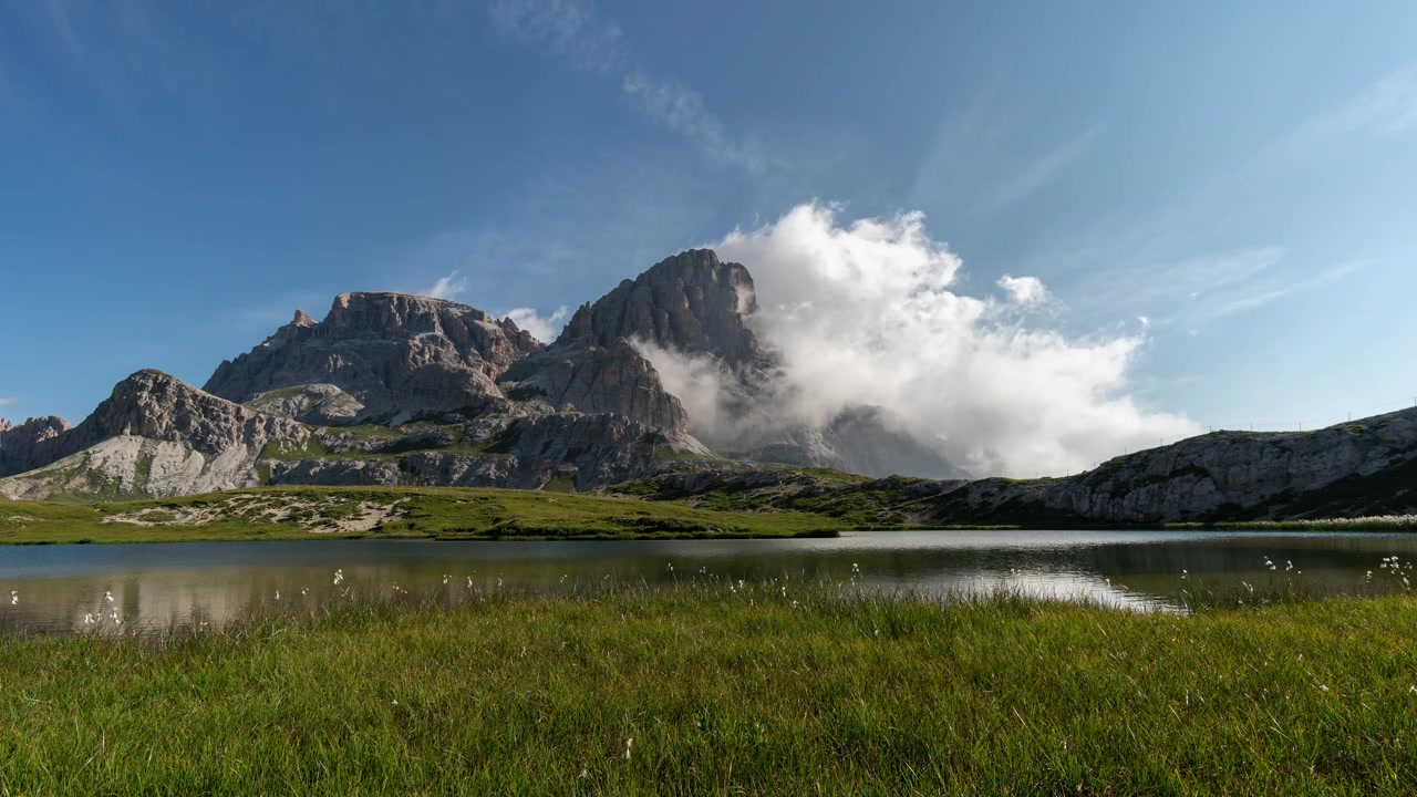 Nuvole che avvolgono una montagna con lago in primo piano TIMELAPSE
