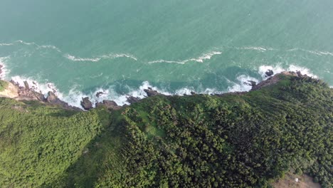 aerial view of a jagged rock island, surrounded with lush green nature and hong kong bay water