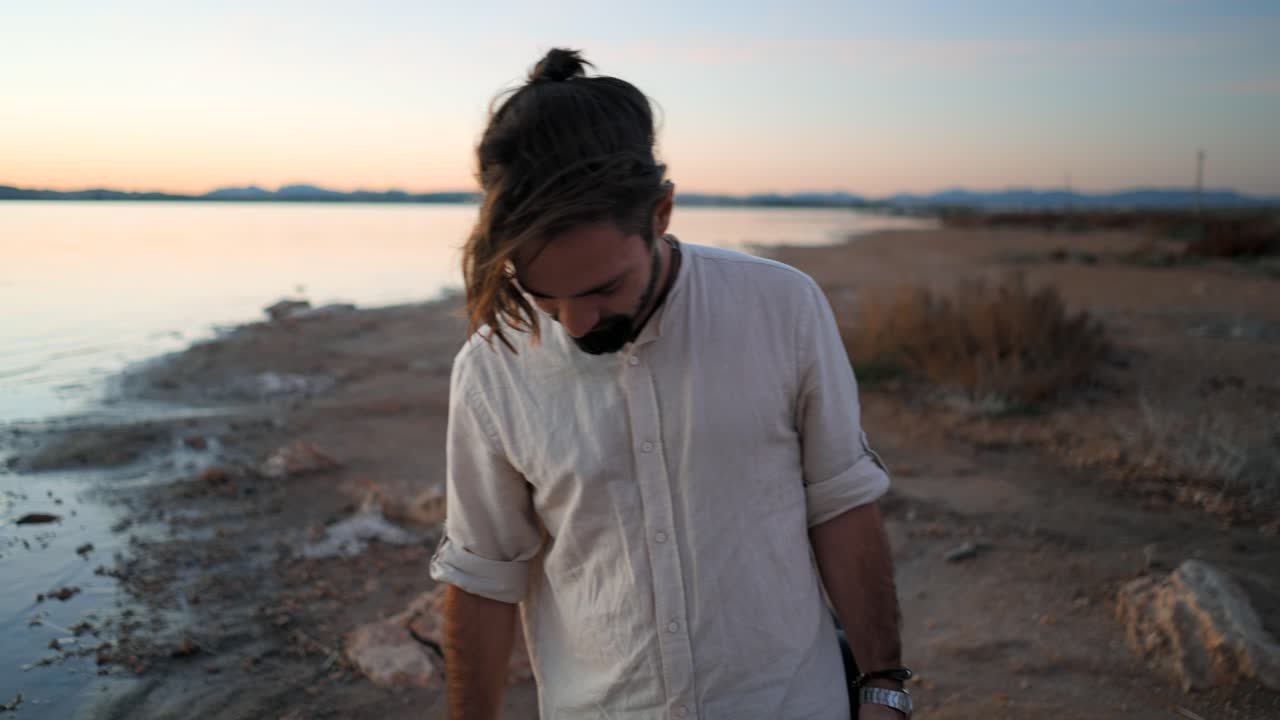 Uomo che cammina in riva al lago al tramonto