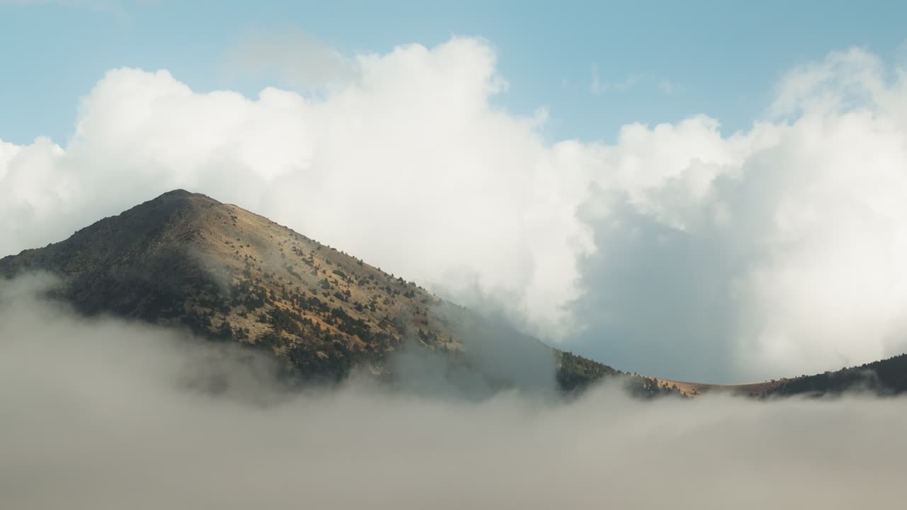 Breathtaking view of a towering mountain peak partially hidden by thick, swirling clouds.