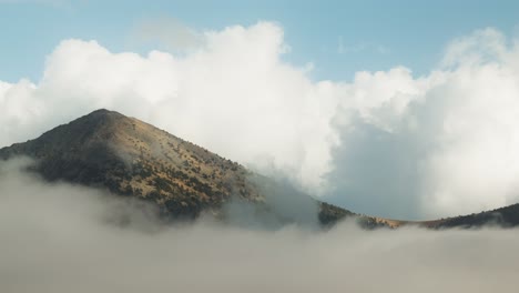 breathtaking view of a towering mountain peak partially hidden by thick, swirling clouds.