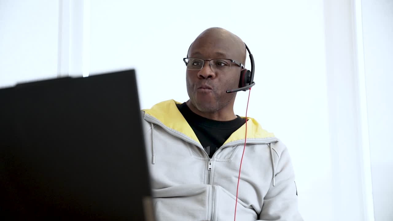 African American businessman enjoying coffee while engaging in a video call from his home office, working remotely on his laptop