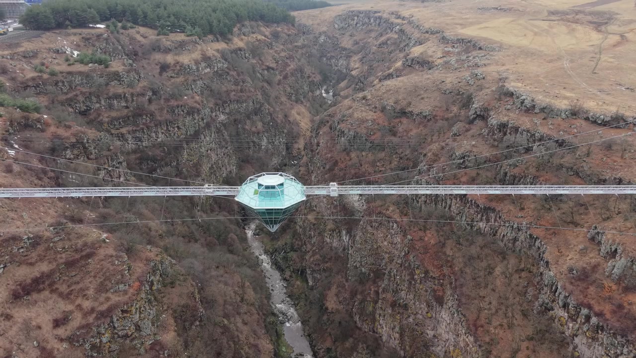 Ripresa verticale con drone che cattura il Ponte di Diamante sopra il canyon Dashbashi o Tsalka prima di inclinarsi per rivelare l'orizzonte lontano e il paesaggio georgiano circostante