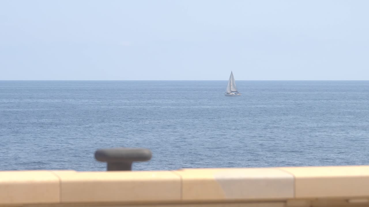 Man Watching Sailboat on Calm Ocean