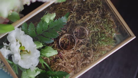 composición con anillos de bodas y artículos naturales en caja