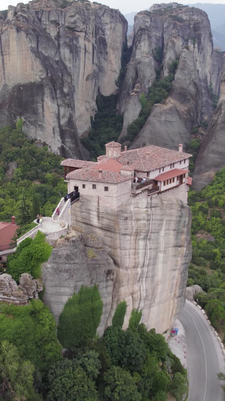 Vertical flyover revealing the monastery complex of Rousanou, perched on Meteora’s cliffs, with sweeping views of the valley below