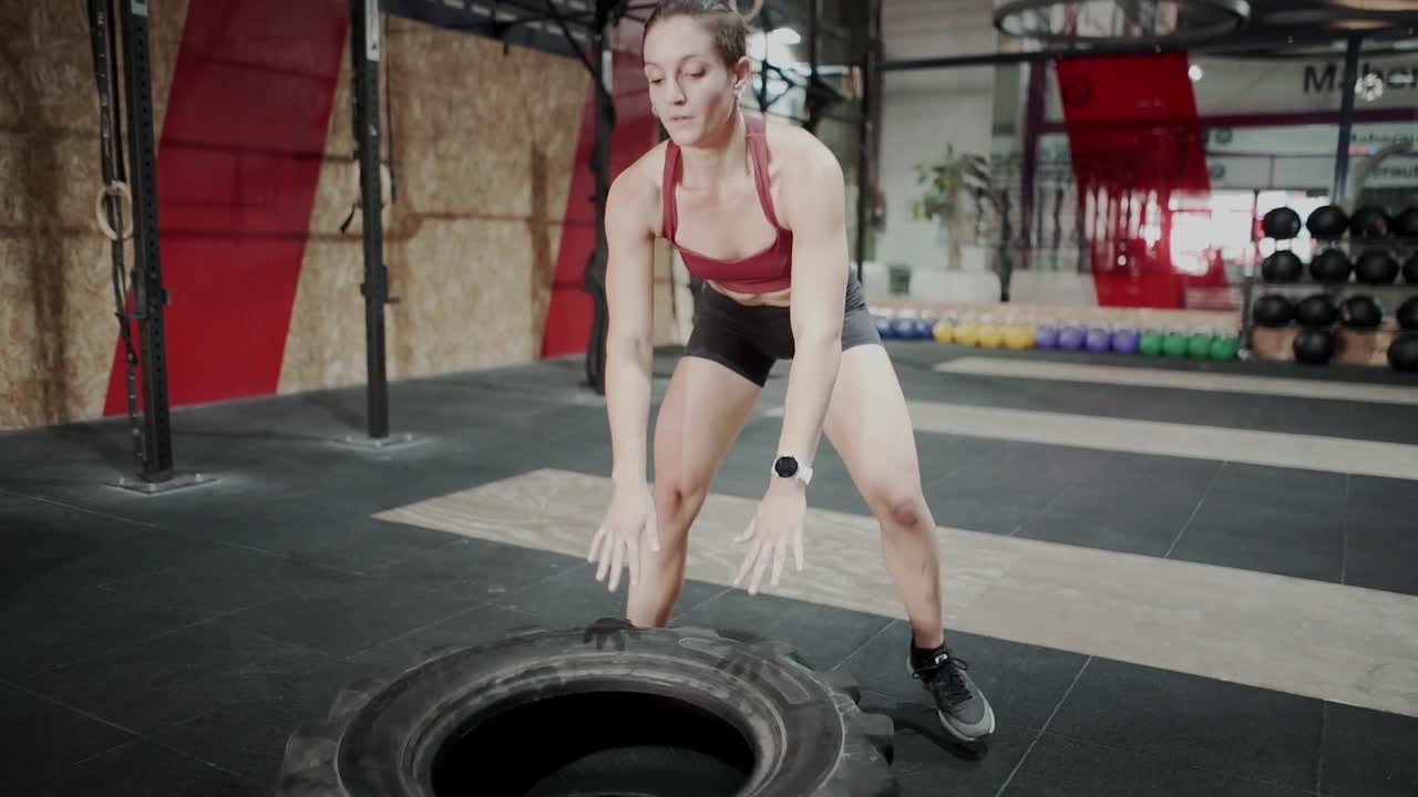 Woman Performing Tire Flip Exercise in Gym