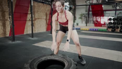 woman performing tire flip exercise in gym