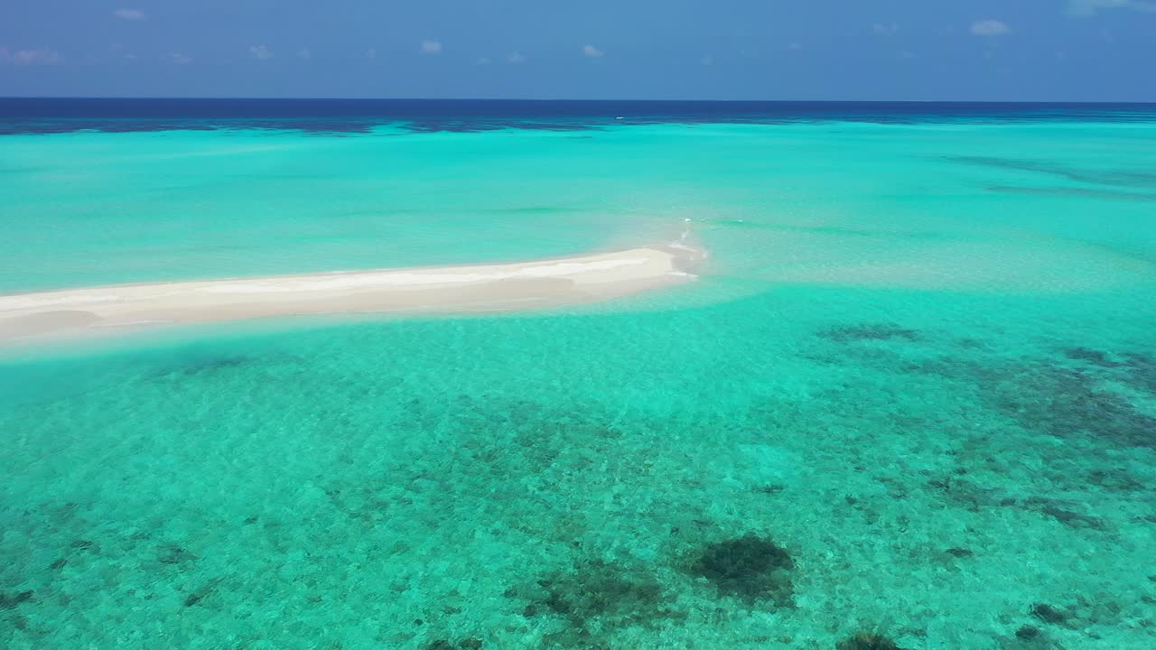 laguna turquesa brillante con aguas claras y tranquilas sobre arrecifes de coral y guijarros alrededor de una franja de arena expuesta bajo el cielo azul en islas turcas y caicos