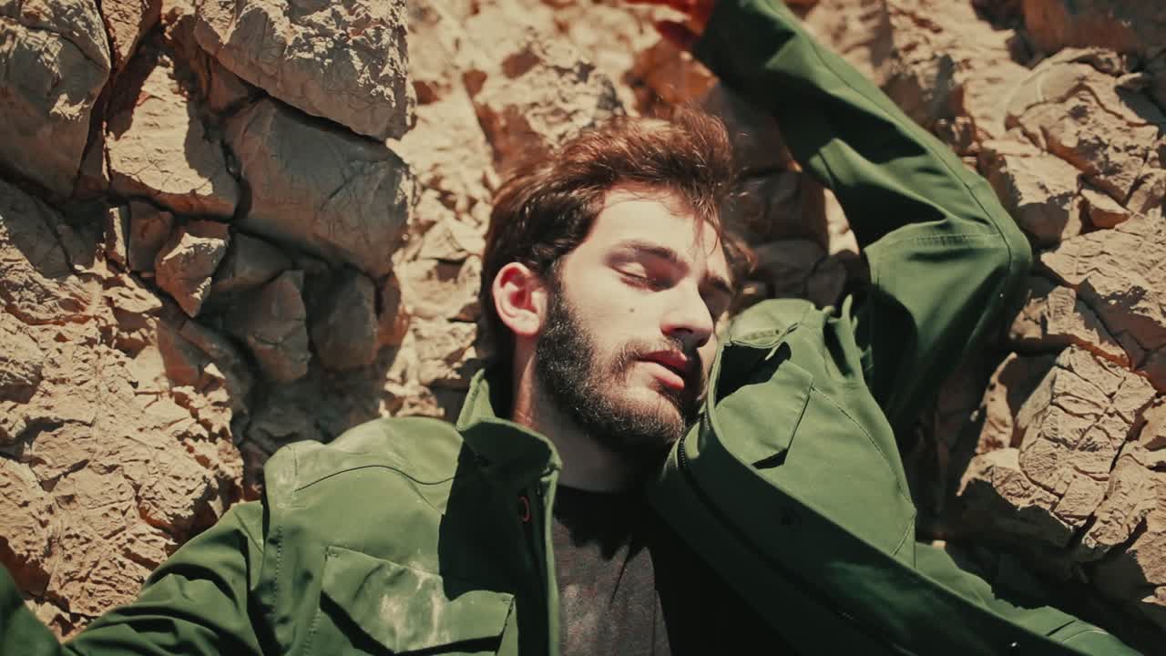 Lifeless body of man with arms spread wide on jagged rocky terrain in desert