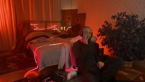 hombre escuchando música en un dormitorio iluminado con neón rojo