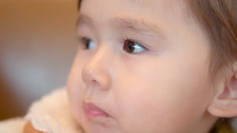 closeup portrait of cute 3-year-old girl with mouth chewing food inside a shopping mall