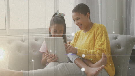 mother and daughter using tablet on couch with digital particles animation