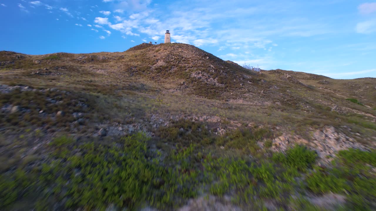 un faro en una colina en el parque nacional de los rocas durante el día, cielo despejado, vista aérea