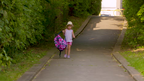 cute little girl taking her backpack off as she walks home from school