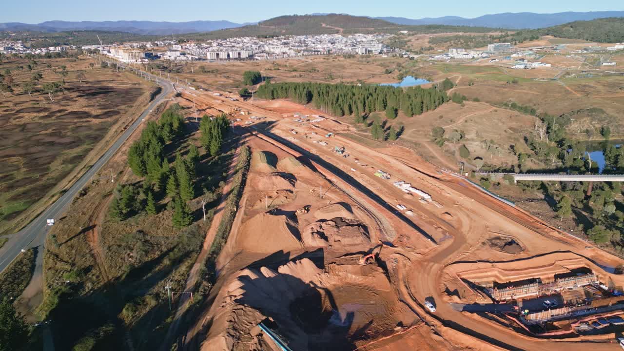 Drone flies straight over a highway construction zone in Canberra with active work and soil preparation in view.
