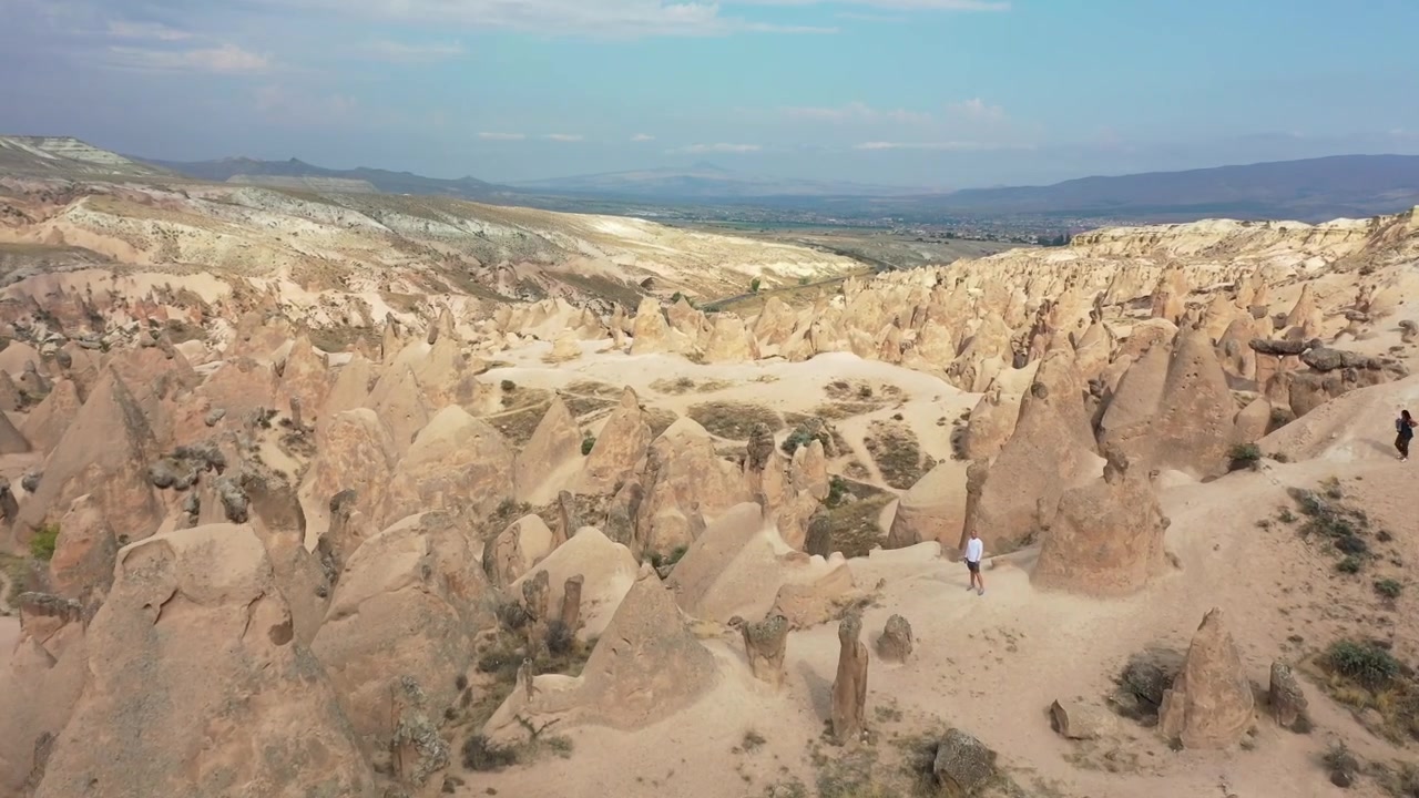 Güneşli bir günde Türkiye, Nevşehir, Kapadokya'daki Kızıl Vadi'de binlerce yoğun sivri peri bacası kaya oluşumunun ve katmanlı kumtaşı kayalıklarının üzerinden yüksekten havadan drone çekimi.