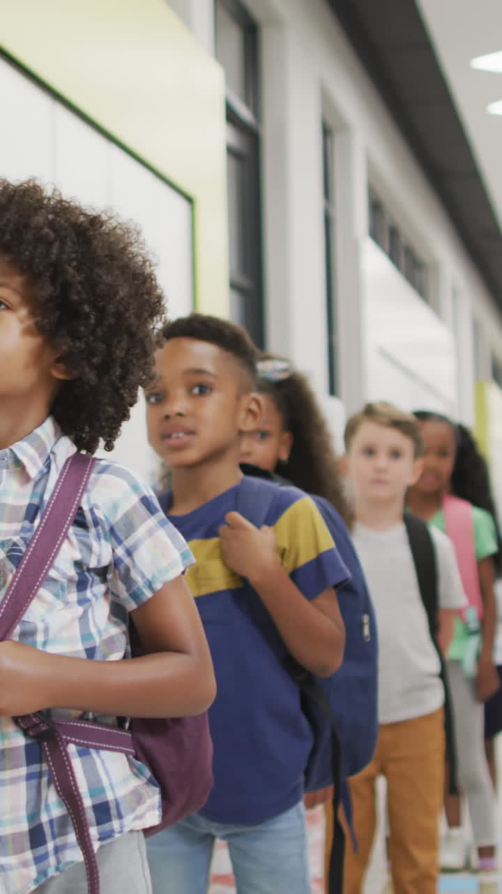 Video of happy diverse pupils standing in row and smiling before entering classroom
